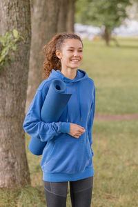 Woman with exercise mat walking in park