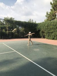 A woman in shorts, a t-shirt and a cap plays tennis. she waved a  racket. the  ball is batting.