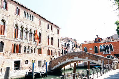 Arch bridge over canal against clear sky in city