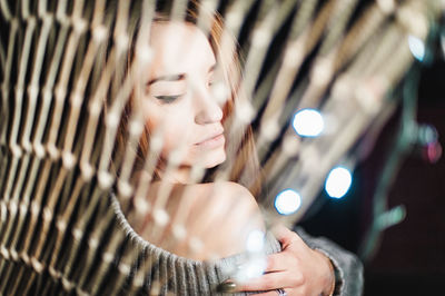 Beautiful woman wearing sweater seen through illuminated netting