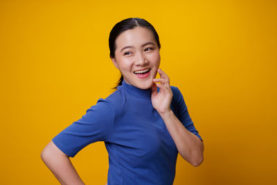 Portrait of smiling young man against yellow background