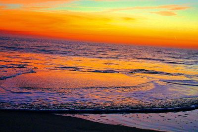 Scenic view of sea against dramatic sky during sunset