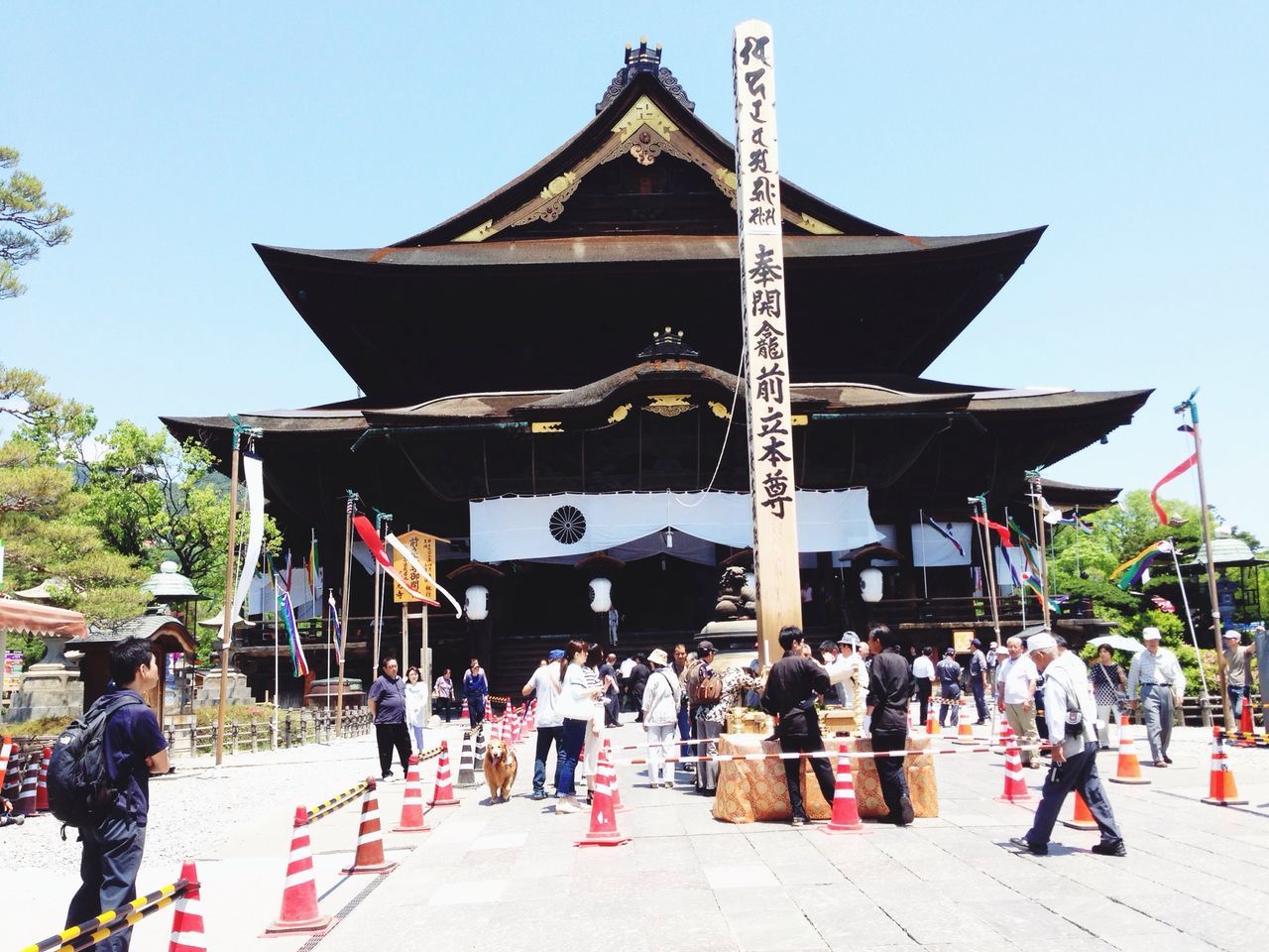 architecture, built structure, building exterior, large group of people, person, religion, tradition, clear sky, place of worship, cultures, men, temple - building, spirituality, lifestyles, travel, leisure activity, day, flag