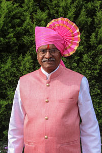 Portrait of man standing by pink umbrella against trees