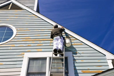 Low angle view of ladder on building against sky