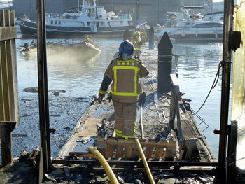 Rear view of firefighter walking on pier over sea