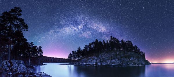 Scenic view of lake and trees against sky at night