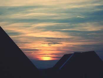 Low angle view of silhouette building against sunset sky