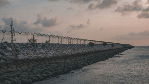 Pier over sea against sky during sunset