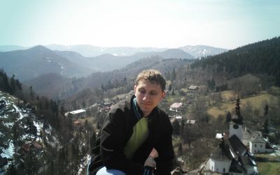 Young man sitting against mountain range during sunny day