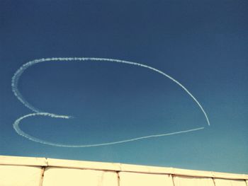 Low angle view of vapor trail against clear blue sky