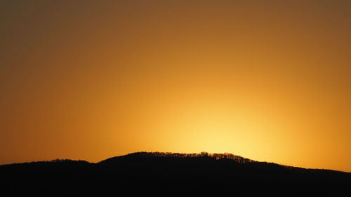 Scenic view of silhouette mountains against orange sky