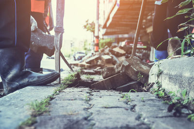 Low section of male workers removing paving stones on footpath