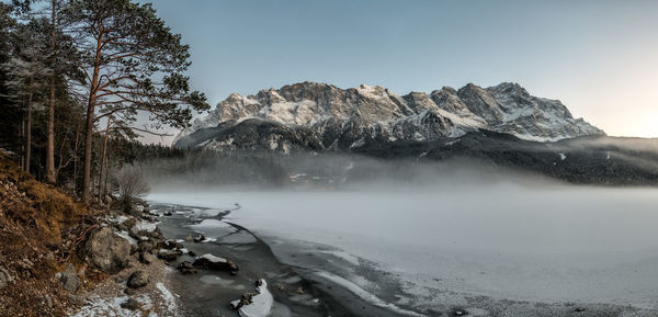 Scenic view of frozen lake by mountains against sky