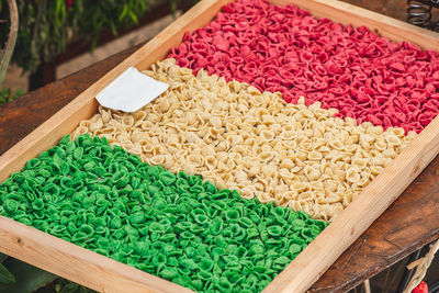 Fresh green, white and red orecchiette or orecchietta pasta drying under the sun on a wooden board