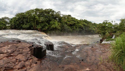 Scenic view of waterfall in forest against sky