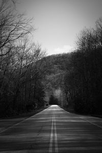 Empty road amidst trees against sky