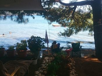 Chairs and table by sea against sky