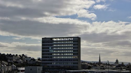 Buildings in city against cloudy sky