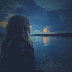 Rear view of woman looking at lake against sky