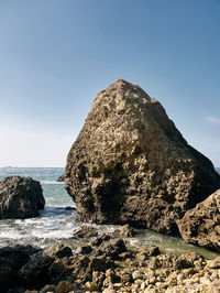 Rock formation on beach against clear sky