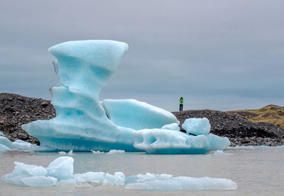 Iceberg floating on lake against sky