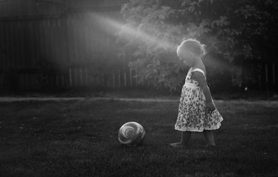 Side view of girl playing with soccer ball in lawn