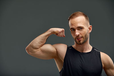 Portrait of young man exercising against black background