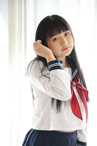 Portrait of young woman standing against curtain