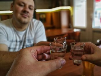 Friends holding tequila shots over table