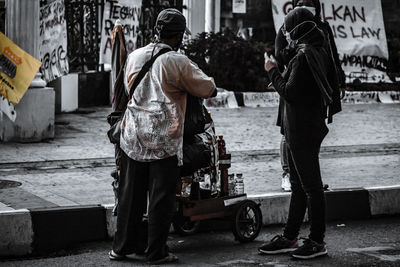 Rear view of men working on street in city