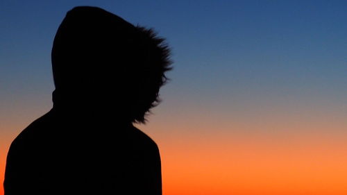 Close-up portrait of silhouette woman against clear sky during sunset