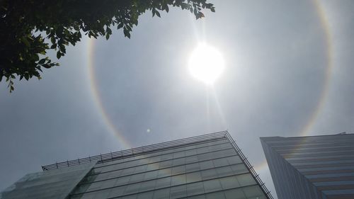 Low angle view of sun shining through clouds