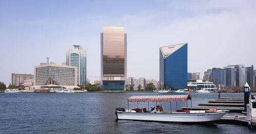 Modern buildings by river against sky in city