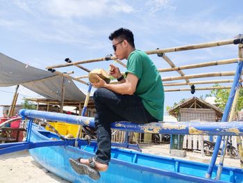 Side view of man holding boat against sky