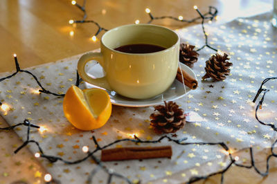 Black coffee by illuminated string lights on table