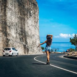 Woman standing by road against sky in city