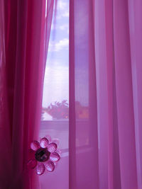 Close-up of pink curtain against window at home