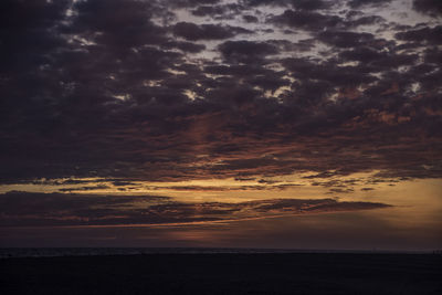 Scenic view of sea against dramatic sky during sunset