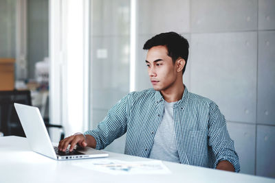 Young man using mobile phone while sitting on table