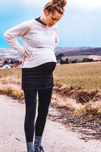 Full length of pregnant woman standing on mountain against sky
