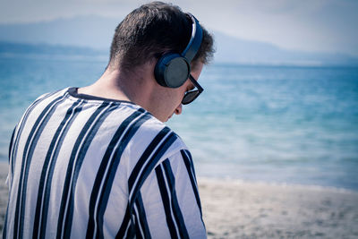 Relaxed man on the beach listening to music with his headphones