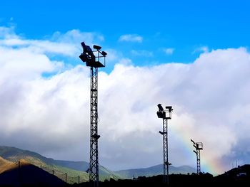 Low angle view of weather vane against cloudy sky