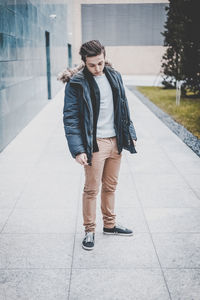 Portrait of young man standing against wall