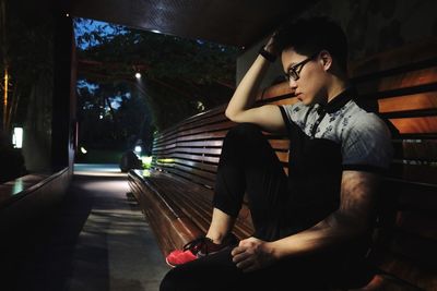 Side view of thoughtful man sitting on bench at night