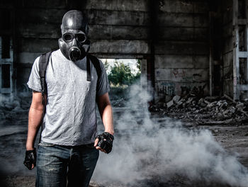 Man wearing gas mask standing under bridge