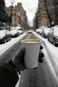 Holding coffee cup on street during winter with gloves