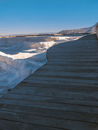 Boardwalk leading towards sea against clear sky