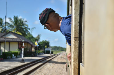 Side view of young man looking at camera