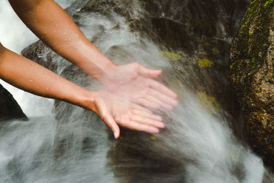 Cropped hands of man on waterfall